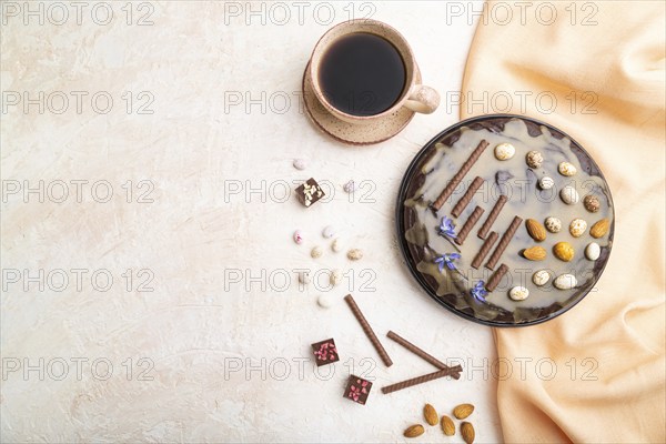 Homemade chocolate brownie cake with caramel cream and almonds with cup of coffee on a white