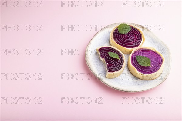 Sweet tartlets with jelly and milk cream on a pastel pink background. Side view, copy space