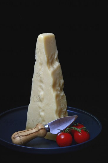 A piece of Parmesan cheese with cheese knife and tomatoes, Italy, Europe
