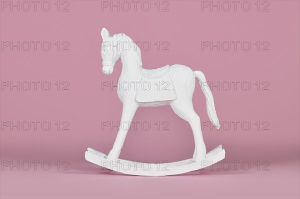 White wooden retro style rocking horse Christmas home decor object on pink background