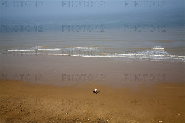 Overhead oblique view of a man walking across wide sandy beach at low tide, Overstrand, Norfolk,