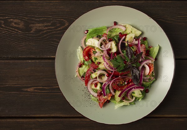 Georgian vegetable salad, tomatoes with cucumbers, red onion, walnut, pomegranate seeds, top view,