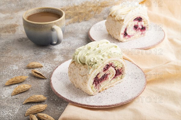 Roll biscuit cake with cream cheese and jam, cup of coffee on brown concrete background and orange