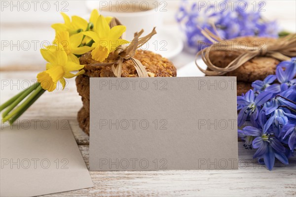 Gray paper business card mockup with oatmeal cookies with spring snowdrop flowers bluebells,
