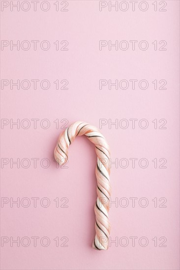 Single cane candy on pink pastel background. copy space, top view, flat lay