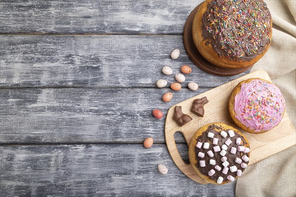 Homemade glazed and decorated easter pies with chocolate eggs and rabbits on a gray wooden