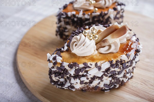Cakes with chocolate chips and cream decorations on wooden board on white background. selective