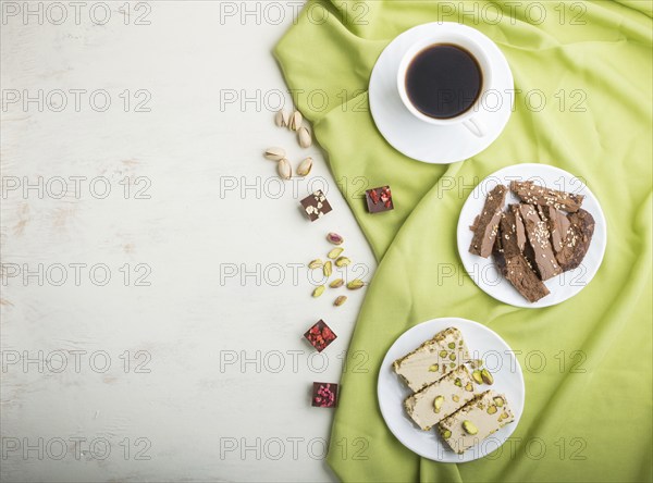 Traditional arabic sweets sesame halva with chocolate and pistachio and a cup of coffee on a white