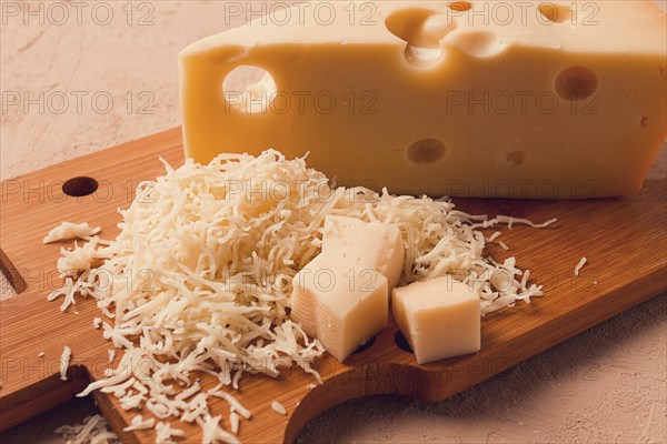 Grated cheese, Maasdam, on a cutting board, grater and cheese knife, close-up, no people