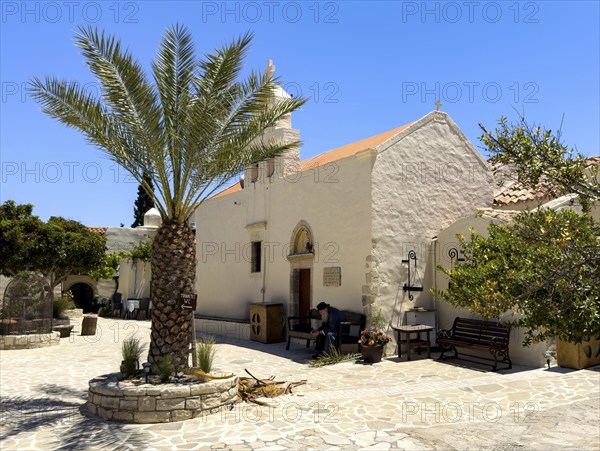 In the foreground cretan date palm (Phoenix theophrasti) behind it two-aisled church Monastery