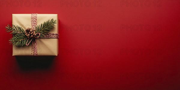 Banner with small Christmas gift box wrapped in graft paper on red background with copy space.