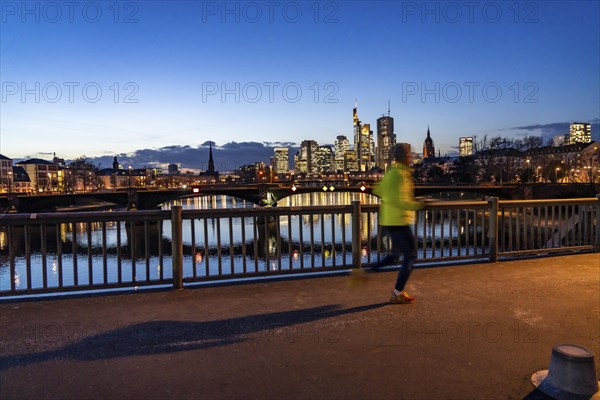 Skyline of the city centre of Frankfurt am Main, jogger on the raft bridge, dusk, river Main,