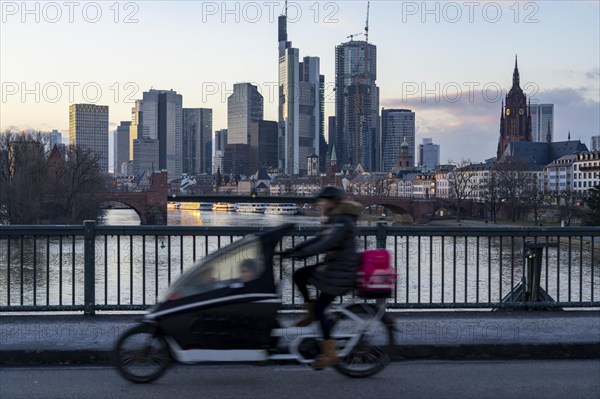 Skyline of the city centre of Frankfurt am Main, cargo bike cyclist on the Ignatz-Bubis-Bridge,