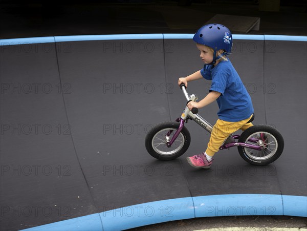 Little girl, 3 years, blonde, helmet, helmet, riding on balance bike, bicycle, skating rink,