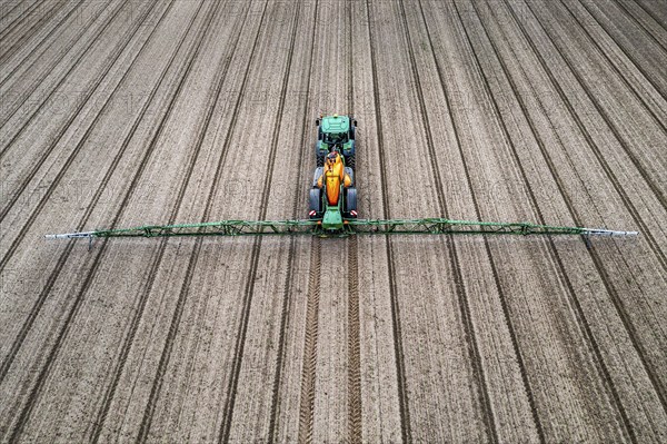 Farmer working a field, crop protection agent being sprayed, field with young sugar beet plants,