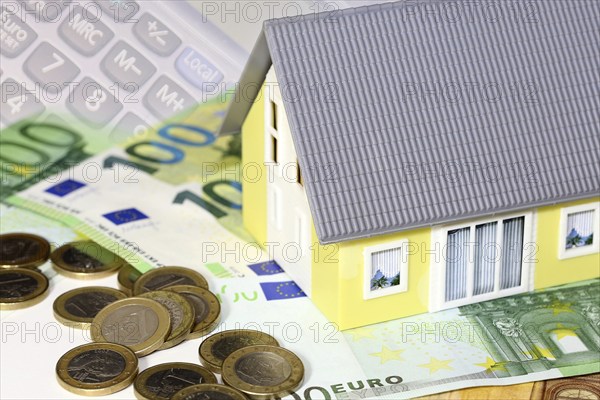 Concept photo with model house, euro notes and coins