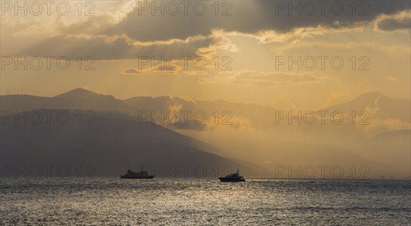Dramatic sunset over the sea with boat silhouettes and cloudy sky, Agia Kyriaki, Nafplio, Nauplia,