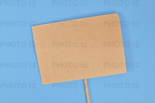 Top view of empty cardboard protest sign on blue background