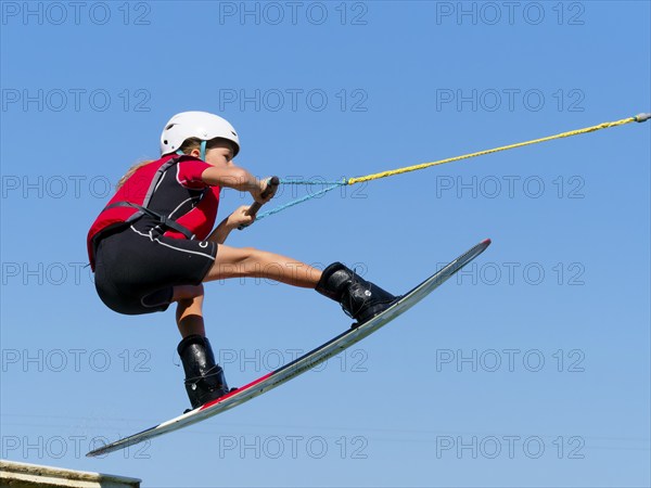 Boy or girl, jump over jump with wakeboard, red life jacket and water sports, water skiing in the