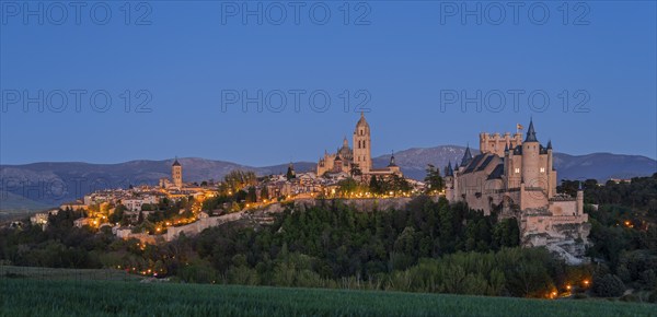 Night scene with an illuminated castle and city in front of dark mountains, a calm and peaceful