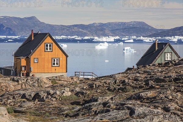 Typical Greenlandic houses in front of icebergs, Inuit settlement, summer, sunny, Uummannaq, West