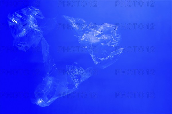 Transparent plastic bags floating underwater in blue ocean sea water, pollution by