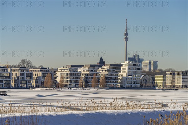 View of the snow-covered and frozen Phoenix Lake and the Florian television tower in Dortmund,