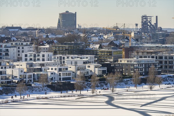 Residential buildings and pedestrians at the snow-covered and frozen Phoenix Lake in Dortmund,