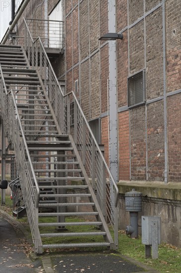 Exterior metal staircase provides access to an industrial building with a brick facade