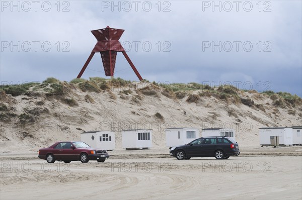 Car traffic on the beach in front of beach huts and sea mark on an early spring day in Blokhus,