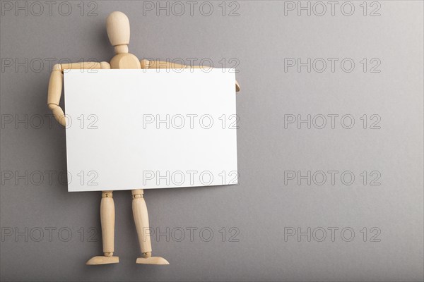 Wooden mannequin holding blank poster on gray pastel background. copy space, isolated, presentation