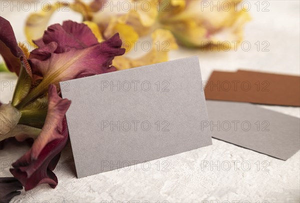 Gray business card with iris flowers on gray concrete background. side view, copy space, still life