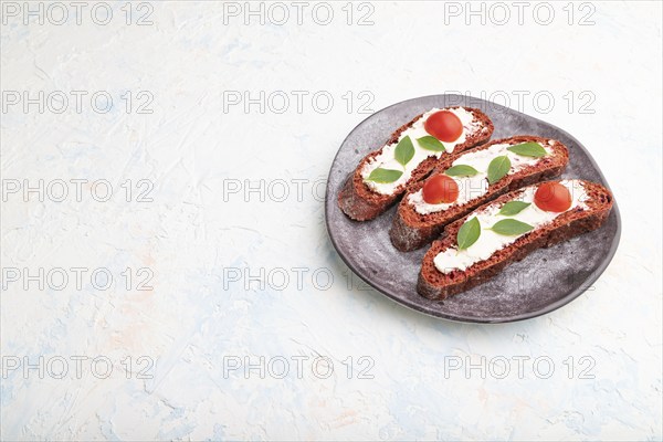 Red beet bread sandwiches with cream cheese and tomatoes on white concrete background. Side view,