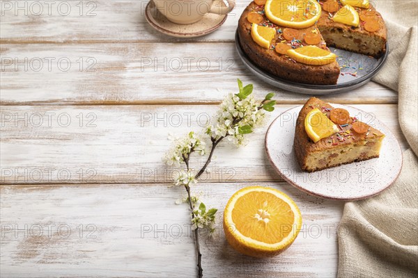 Orange cake and a cup of coffee on a white wooden background and linen textile. Side view, copy