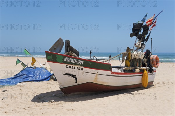 Traditional fishing boat with colourful flags on the beach, looking into the distant blue coloured
