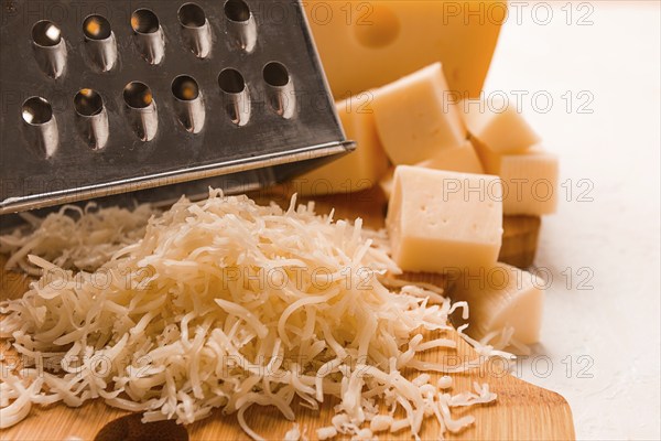 Grated cheese, Maasdam, on a cutting board, grater and cheese knife, close-up, no people