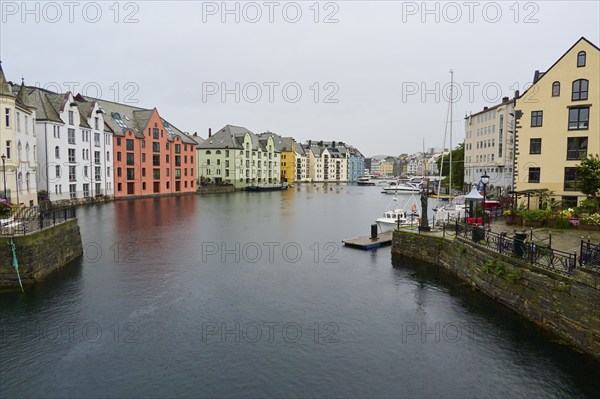 City view with coloured buildings by the sea, boats and bridge in the background, Alesund, Fylke,
