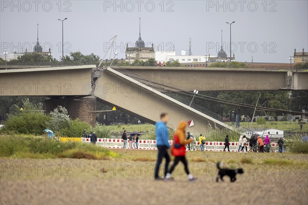 Passers-by look at the partially collapsed Carola Bridge from the Königsufer in Dresden, 11/09/2024