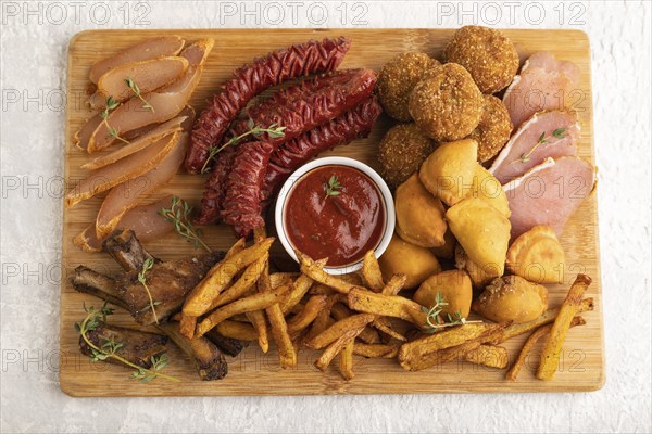 Set of snacks: sausages, fried potatoes, meat balls, dumplings, basturma on a cutting board on a