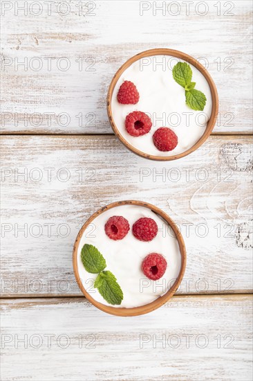 Yogurt with raspberry in clay cups on white wooden background. top view, flat lay, close up