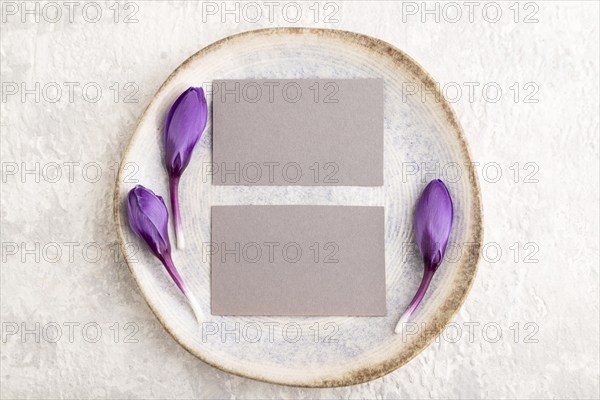 Gray paper invitation card, mockup with crocus flowers on ceramic plate and gray concrete