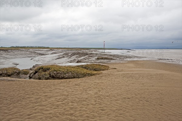 Muddy channel of the River Brue at low tide at its mouth at Burnham on Sea, Somerset, England,