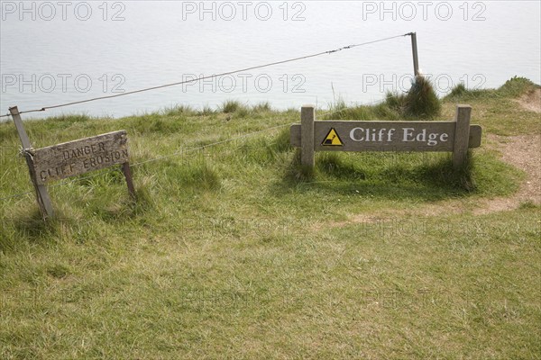 Wooden signs warning of the danger of cliff erosion at the top of the sheer cliffs at Beachy Head,