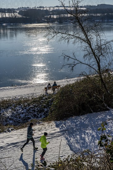 Winter in the Ruhr area, Lake Baldeney, snow-covered, partly frozen lake, walkers on the lakeside