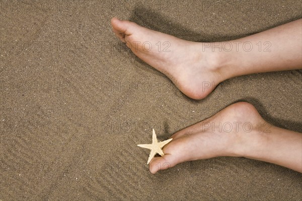 Two feet lying in the sand, starfish between the toes, holiday, North Sea coast, North Sea coast,