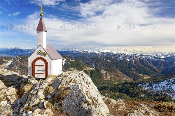 Whitewashed miniature chapel on the Hochgern summit in the Chiemgau Alps under partly cloudy skies