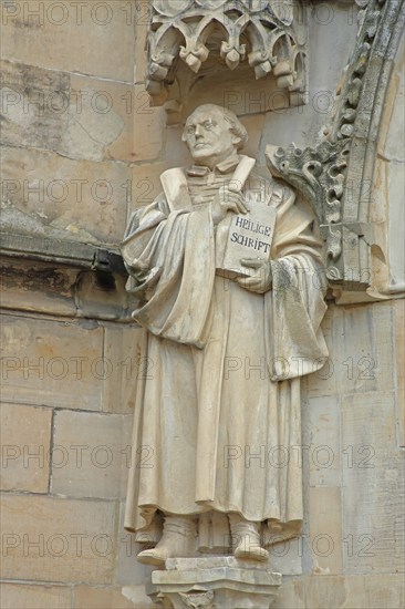 Sculpture and monument of Martin Luther with Bible, Holy Scripture, book at the portal of St