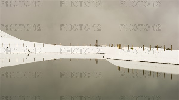 After snowfall in May: Riezler Alpsee, an artificial lake, snow pond, feeds the snow cannons that