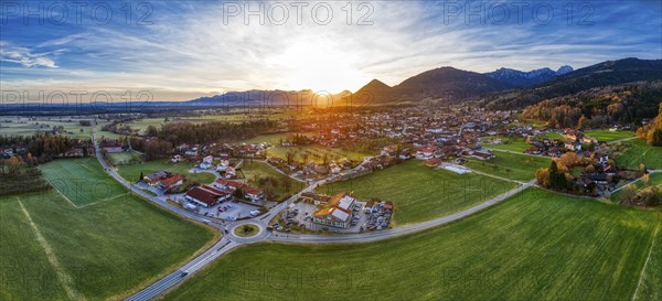 Aerial view of a village in an expansive landscape at sunset, surrounded by mountains, Bad
