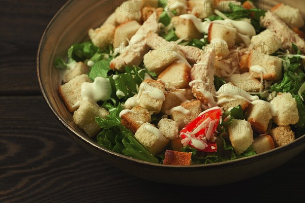 Fresh traditional Caesar salad, with chicken, on a wooden background, Top view, toned, horizontal
